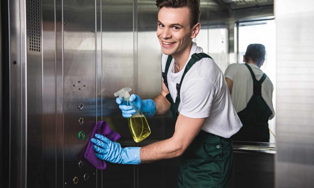 young-cleaning-company-worker-cleaning-elevator-and-smiling-at-camera.jpg